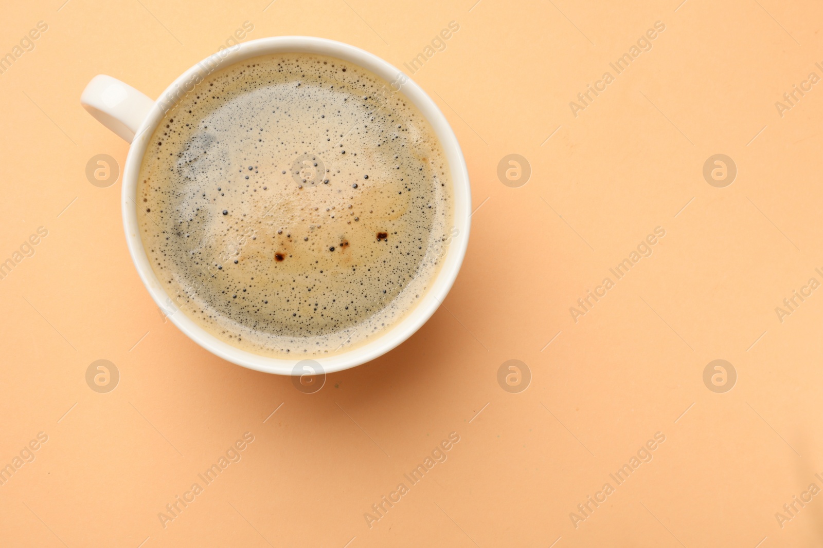 Photo of Fresh coffee in cup on beige background, top view. Space for text