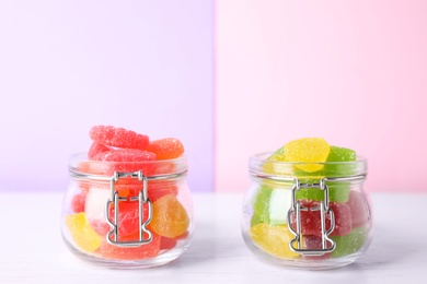Yummy candies in glass jars on white table