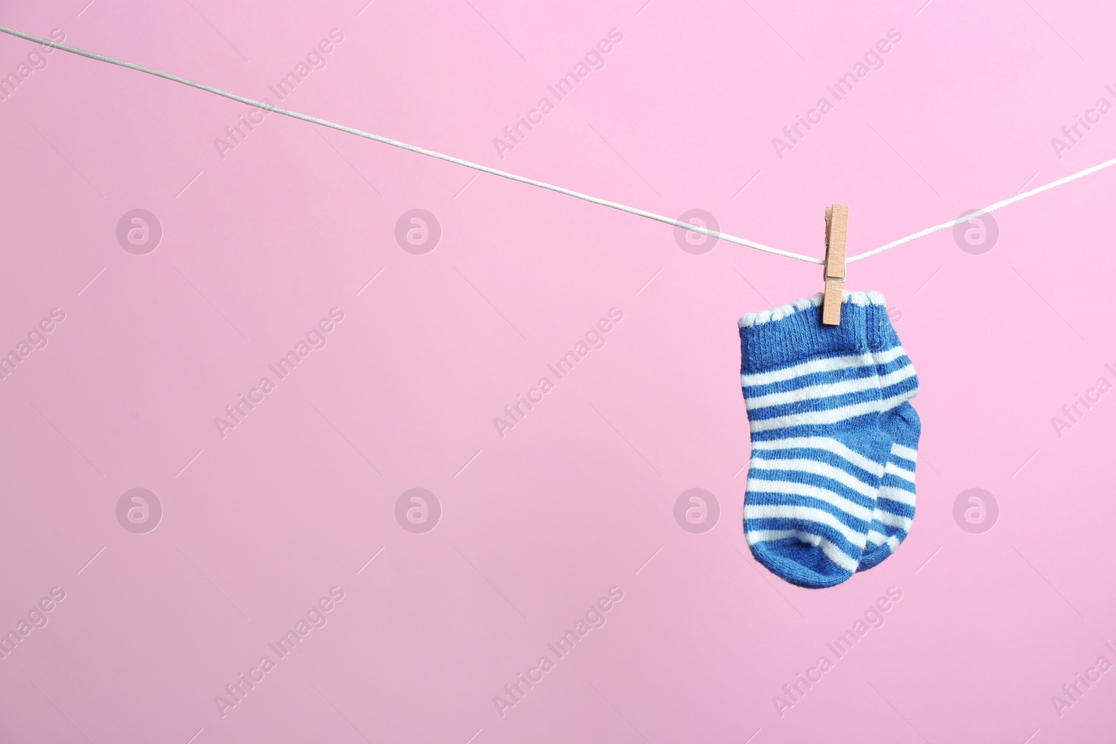 Photo of Small socks hanging on washing line against color background, space for text. Baby accessories