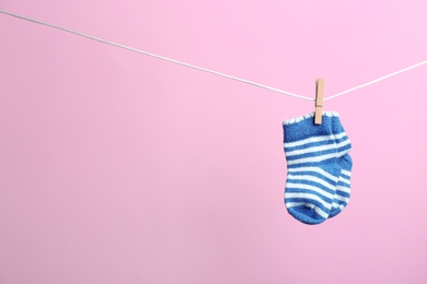 Small socks hanging on washing line against color background, space for text. Baby accessories