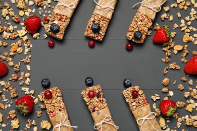 Tasty granola bars and ingredients on grey wooden table, flat lay. Space for text