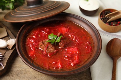 Stylish brown clay bowl with Ukrainian borsch served on wooden table