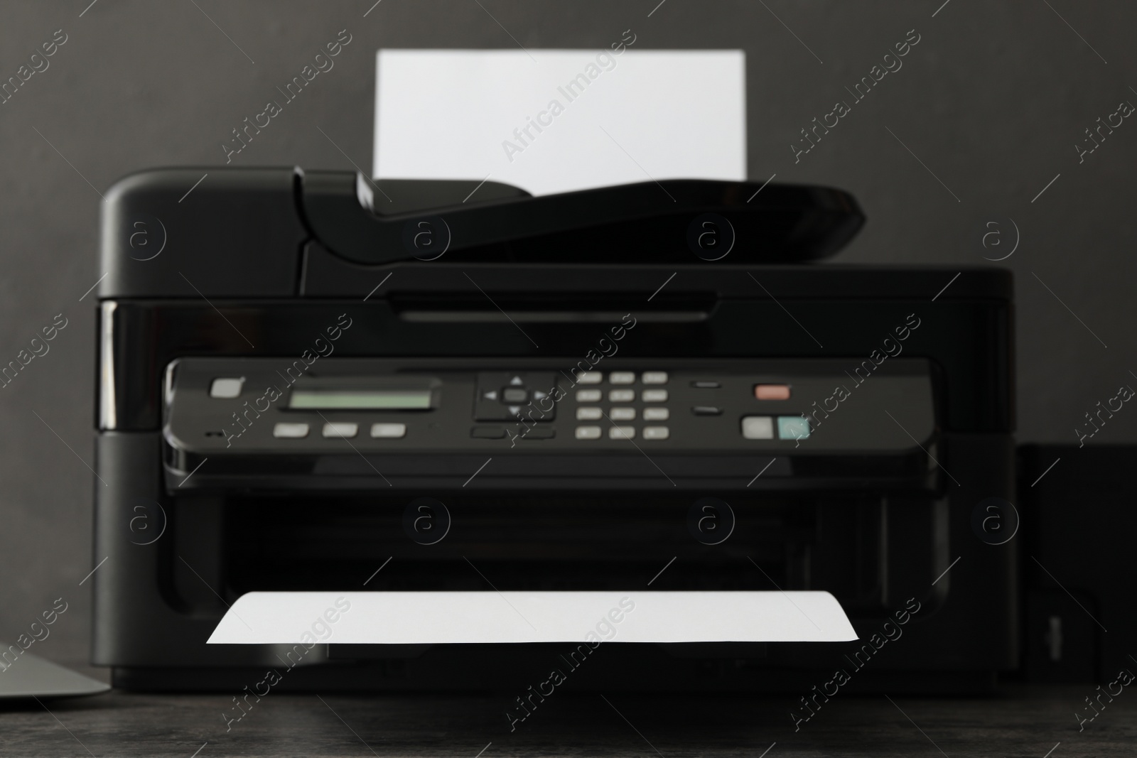 Photo of Modern printer with paper on grey table, closeup