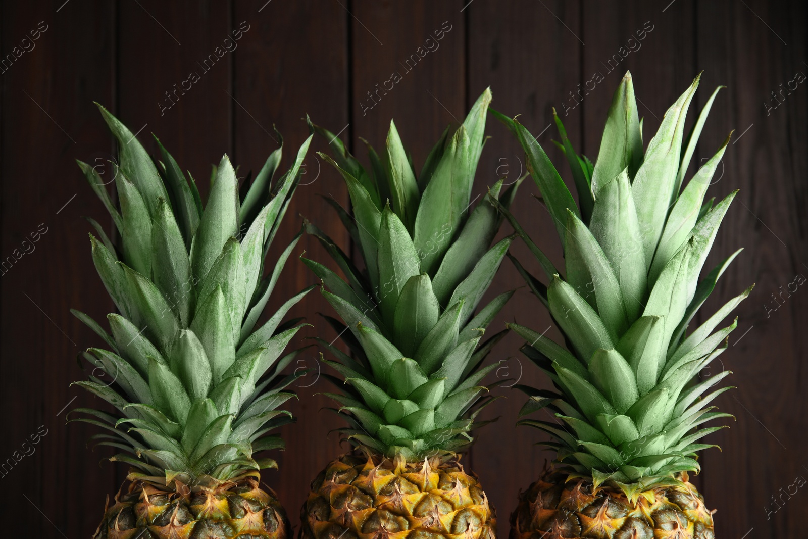 Photo of Fresh ripe juicy pineapples on wooden background