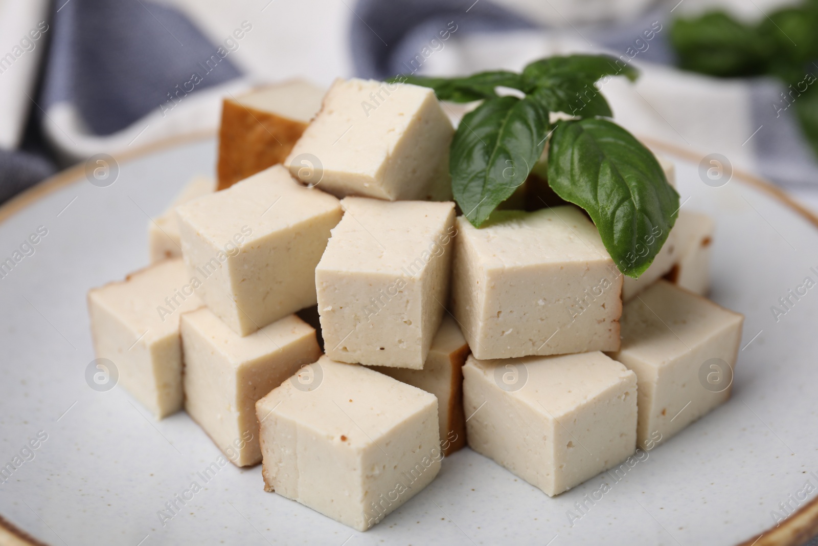 Photo of Plate with delicious smoked tofu and basil, closeup