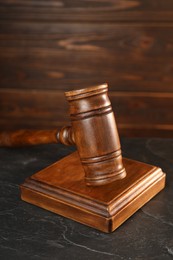 Photo of Wooden gavel and sound block on dark textured table, closeup