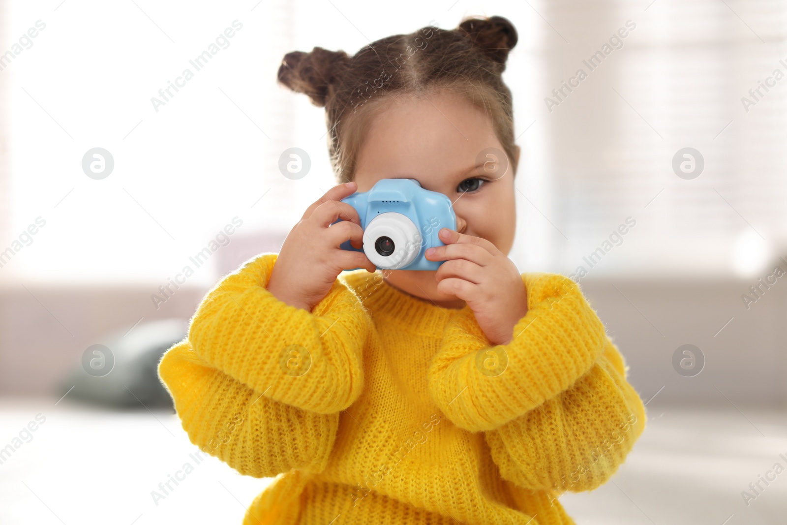 Photo of Little photographer taking picture with toy camera at home