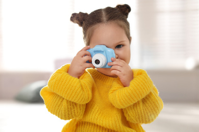 Photo of Little photographer taking picture with toy camera at home