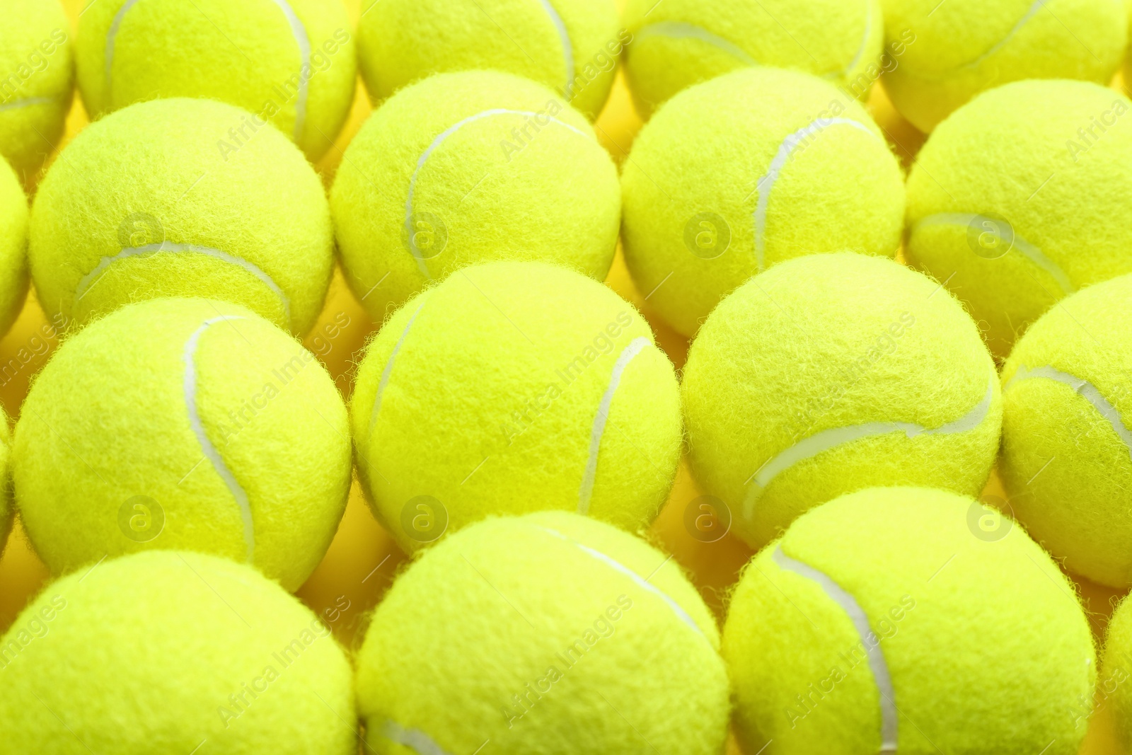 Photo of Tennis balls on yellow background, closeup. Sports equipment
