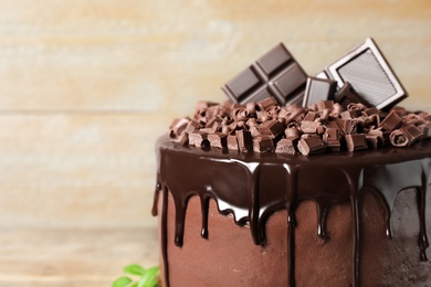 Photo of Freshly made delicious chocolate cake against wooden background, closeup. Space for text