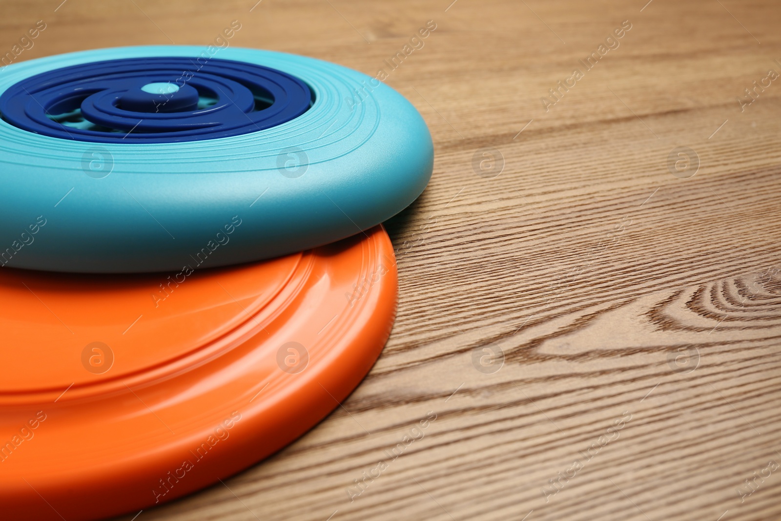 Photo of Plastic frisbee disks on wooden background, closeup. Space for text