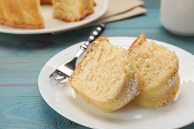 Photo of Pieces of delicious sponge cake and fork on light blue wooden table, closeup