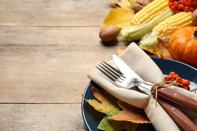 Seasonal table setting with autumn leaves and vegetables on wooden background, space for text. Thanksgiving Day