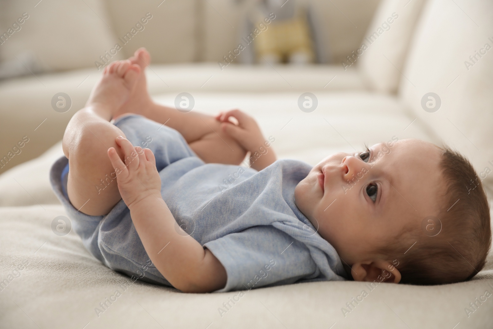 Photo of Cute little baby lying on sofa indoors