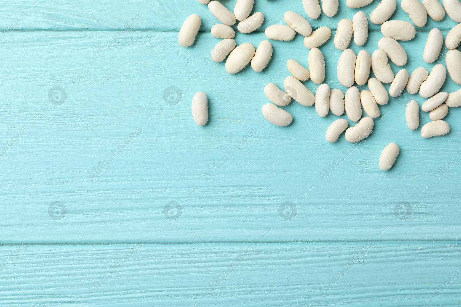 Photo of Raw beans and space for text on light blue wooden background, flat lay. Vegetable seeds