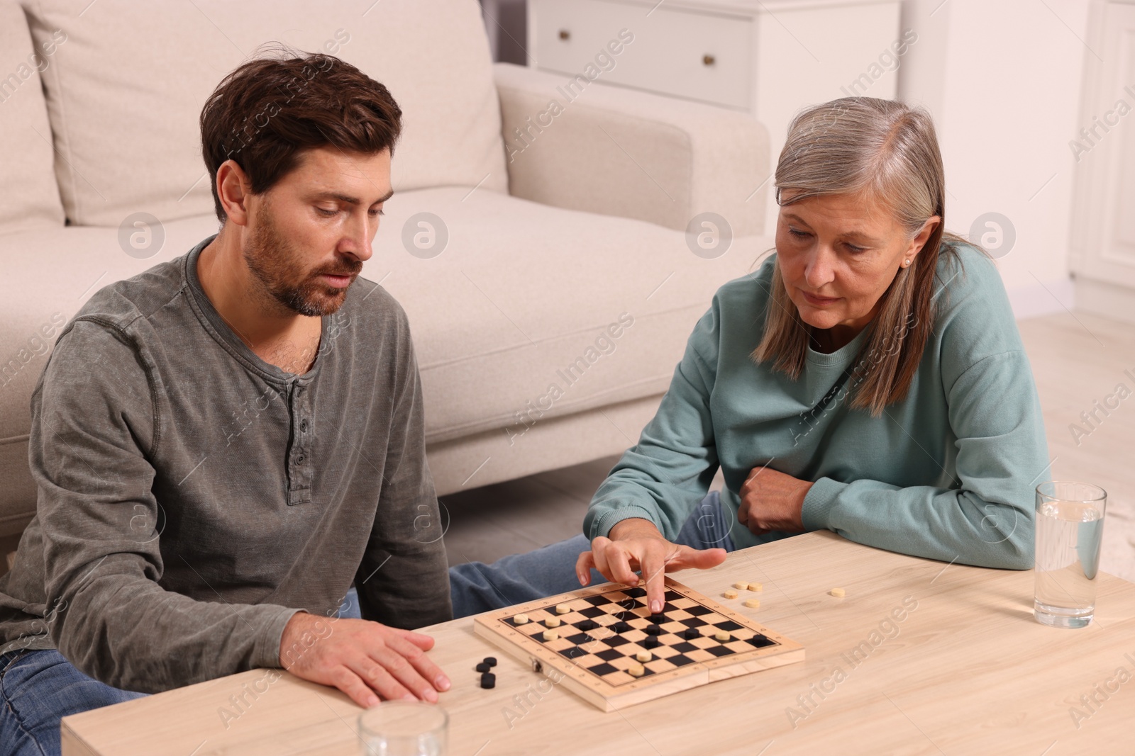 Photo of Family playing checkers at coffee table in room