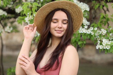 Photo of Beautiful woman in straw hat near blossoming tree on spring day