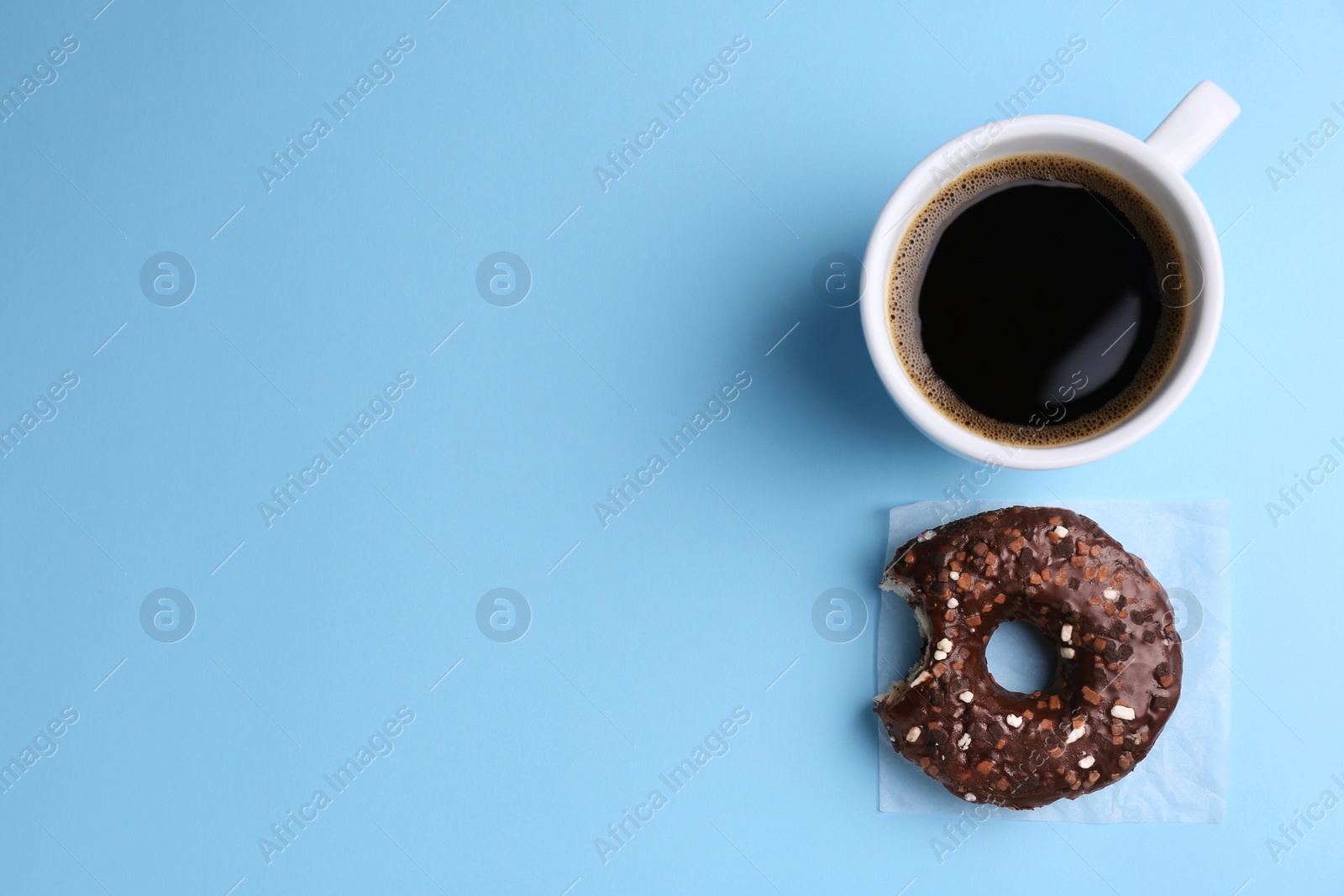 Photo of Tasty donut and cup of coffee on light blue background, flat lay. Space for text