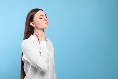 Young woman with sore throat on light blue background. Space for text