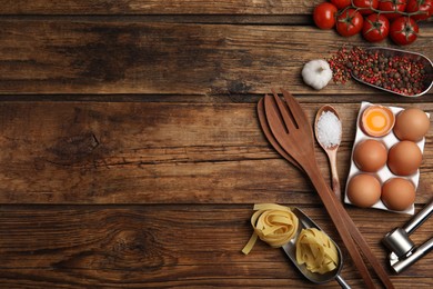 Photo of Cooking utensils and ingredients on wooden table, flat lay. Space for text