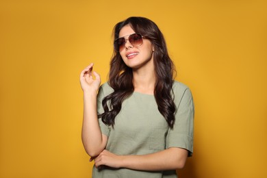 Photo of Happy beautiful woman with stylish sunglasses on orange background