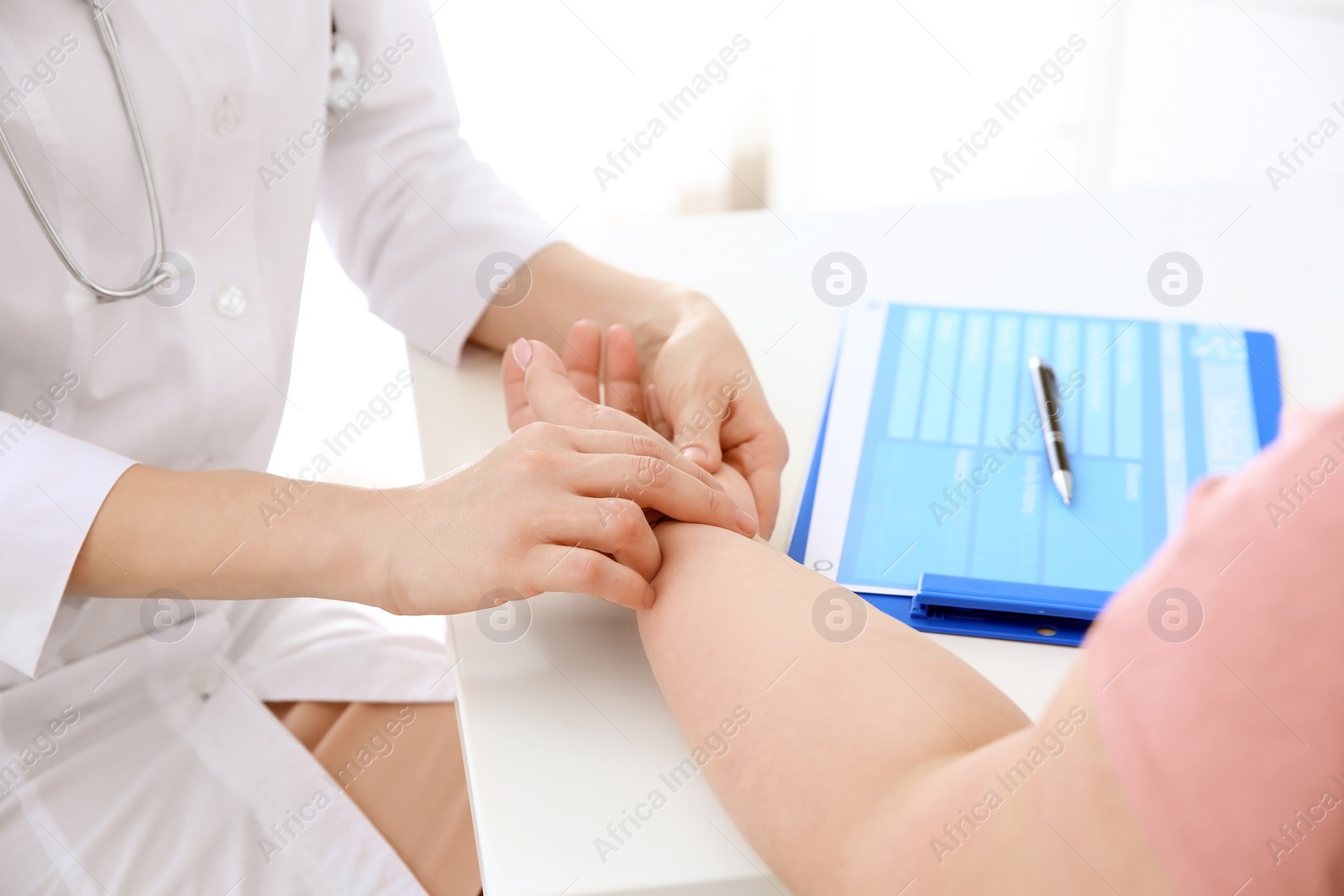 Photo of Female doctor taking pulse of overweight woman in clinic