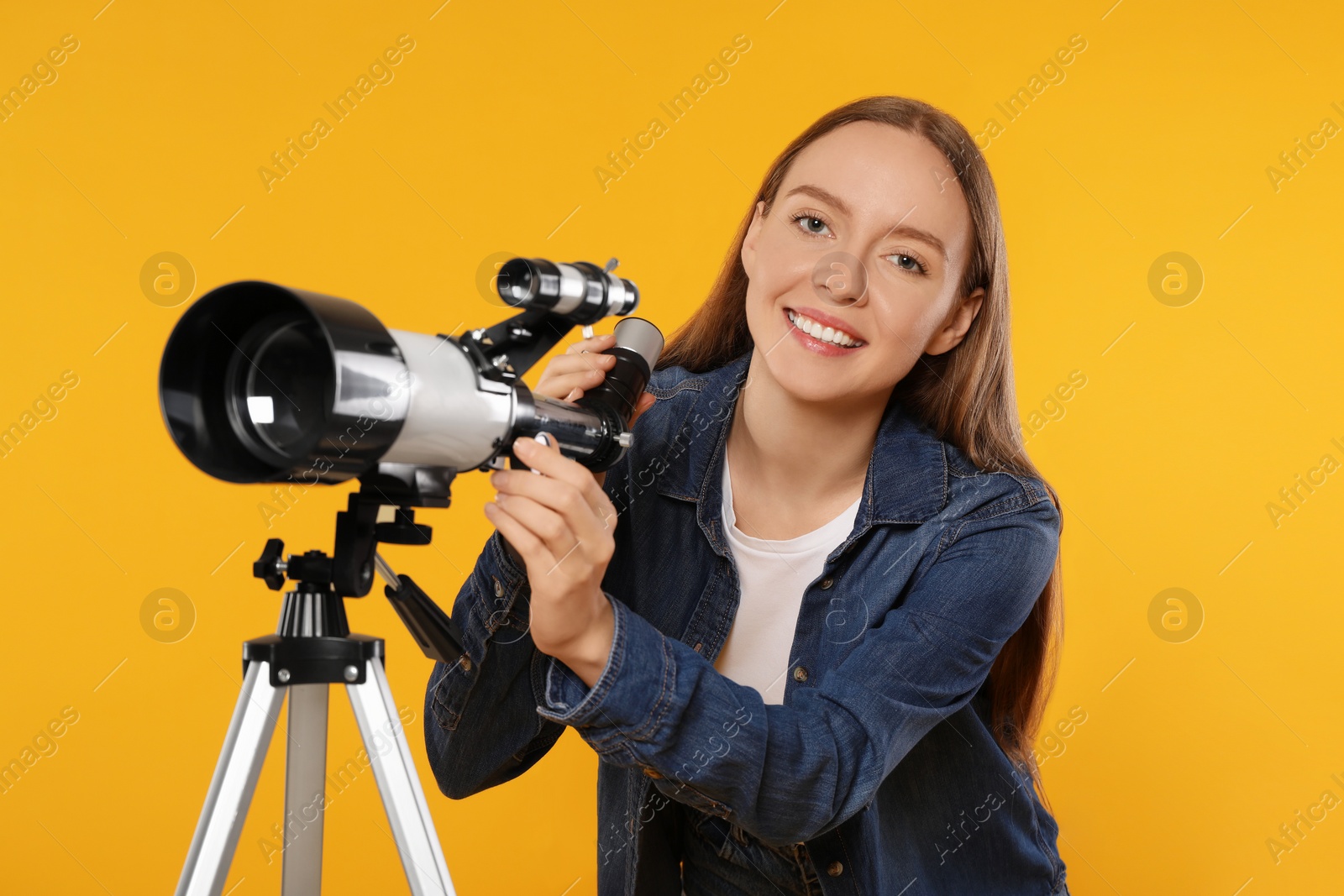 Photo of Happy astronomer with telescope on orange background