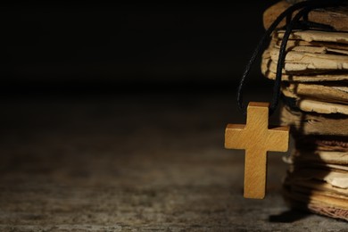 Wooden Christian cross and old books on table, closeup. Space for text