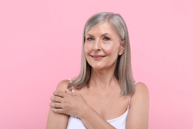 Portrait of beautiful senior woman on pink background