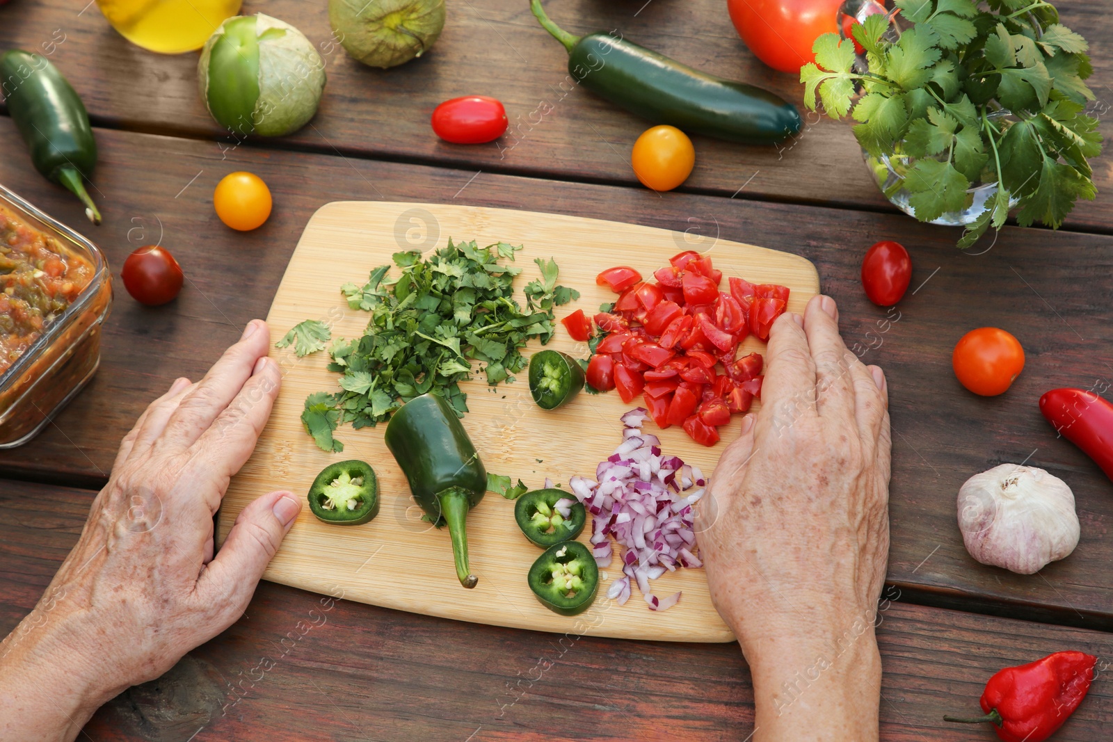 Photo of Woman preparing tasty salsa sauce at wooden table, above view