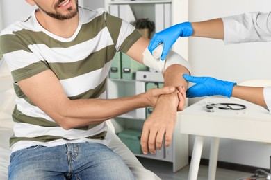 Photo of Doctor applying bandage onto patient's arm at hospital, closeup