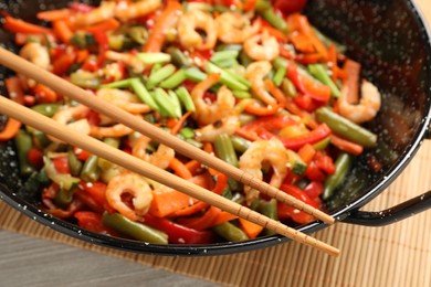 Photo of Shrimp stir fry with vegetables in wok on table, closeup