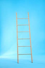 Photo of Modern wooden ladder on light blue background