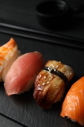 Photo of Plate with delicious nigiri sushi on black table, closeup
