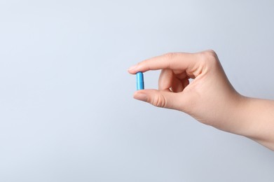 Photo of Woman with pill on light grey background, closeup. Space for text