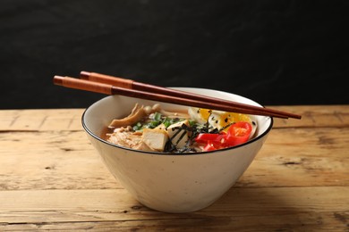 Photo of Bowl of delicious ramen and chopsticks on wooden table. Noodle soup