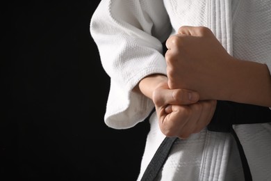 Photo of Man wearing keikogi and black belt on dark background, closeup view with space for text. Martial arts uniform