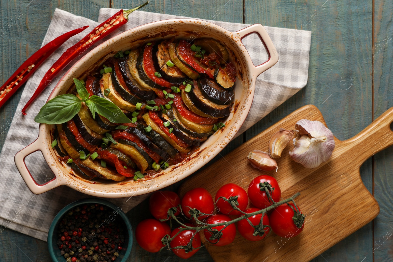 Photo of Delicious ratatouille and ingredients on wooden table, flat lay