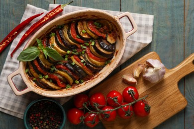 Photo of Delicious ratatouille and ingredients on wooden table, flat lay