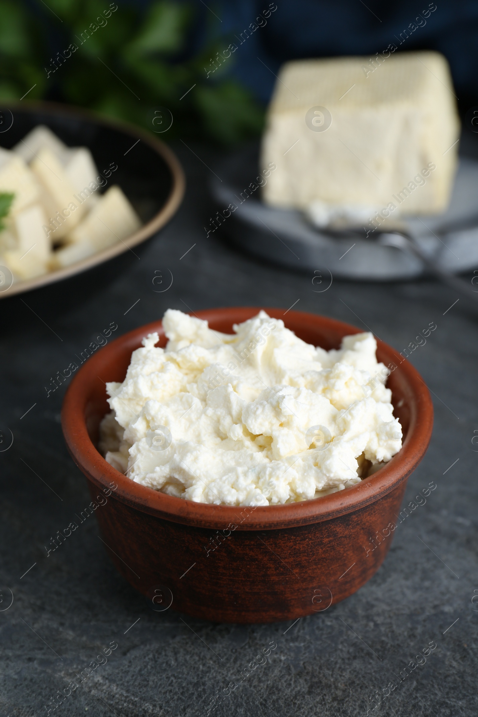 Photo of Delicious tofu cream cheese in bowl on black table, closeup