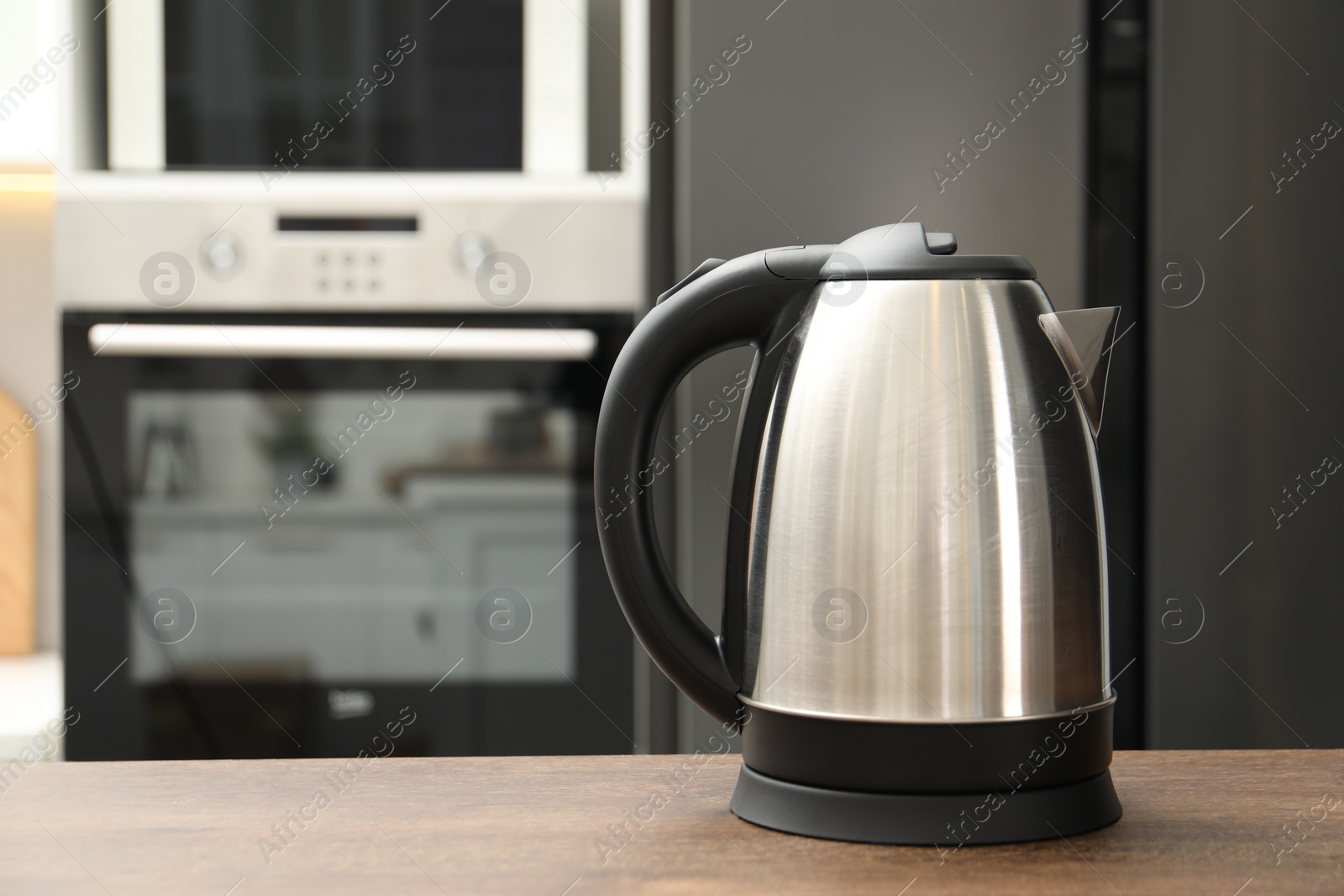 Photo of Modern electric kettle on table in kitchen. Space for text