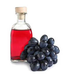 Photo of Glass bottle with wine vinegar and fresh grapes on white background