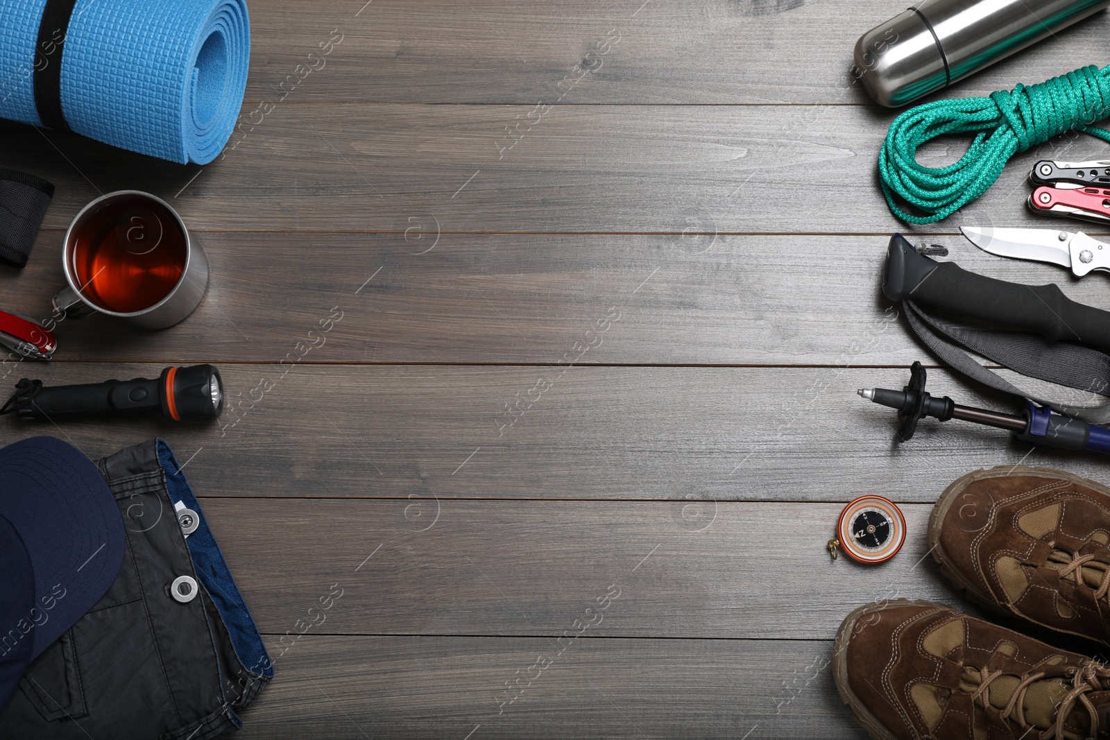 Photo of Flat lay composition with trekking poles and other hiking equipment on wooden background, space for text