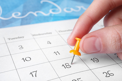 Photo of Woman marking date in calendar with drawing pin, closeup