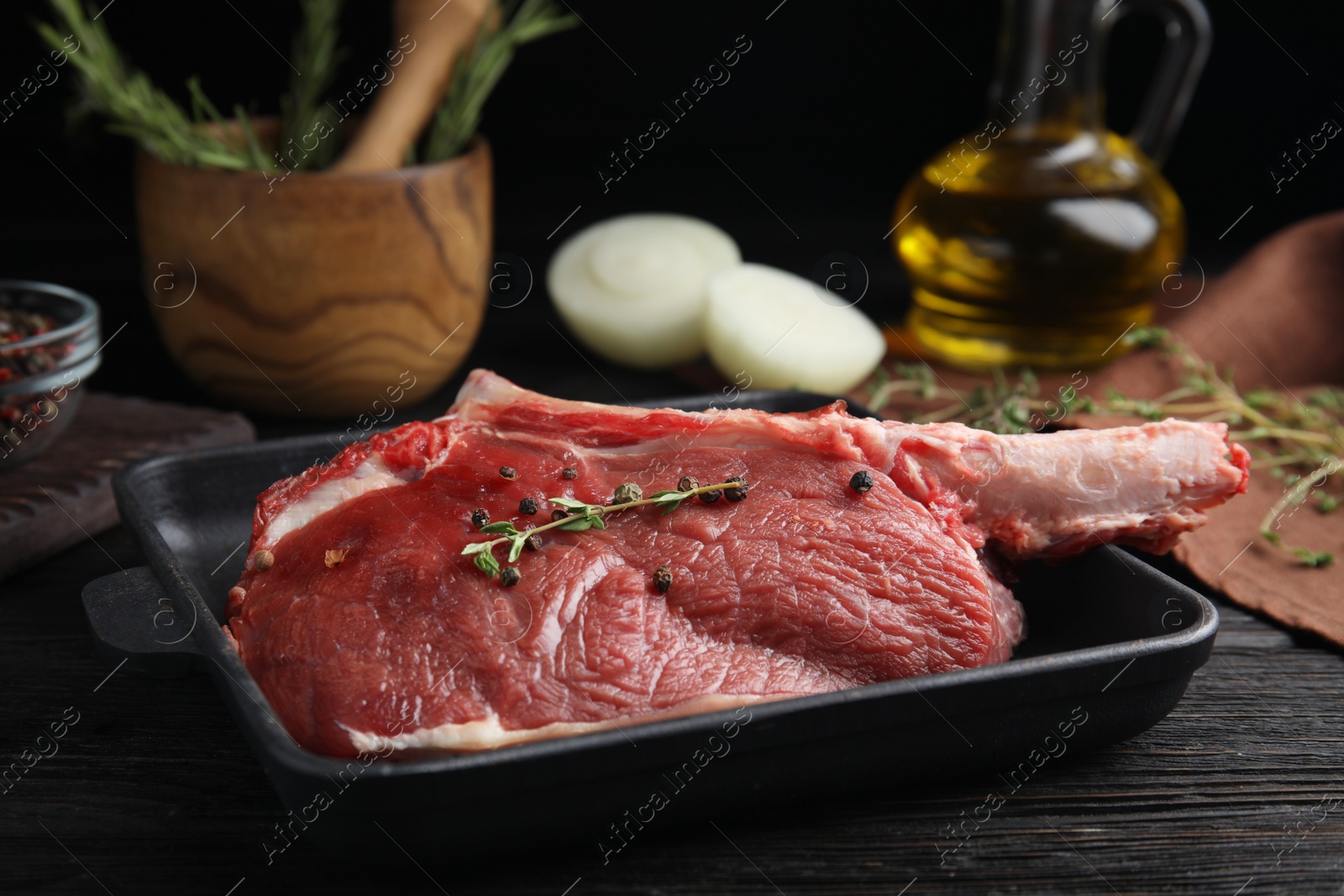 Photo of Fresh raw beef cut in baking dish on black wooden table, closeup