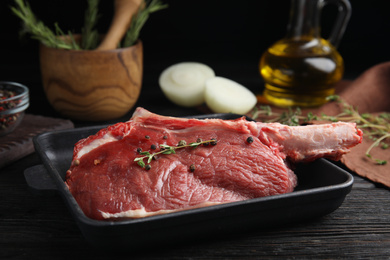 Fresh raw beef cut in baking dish on black wooden table, closeup