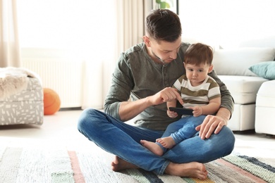 Dad and his son with phone on carpet at home