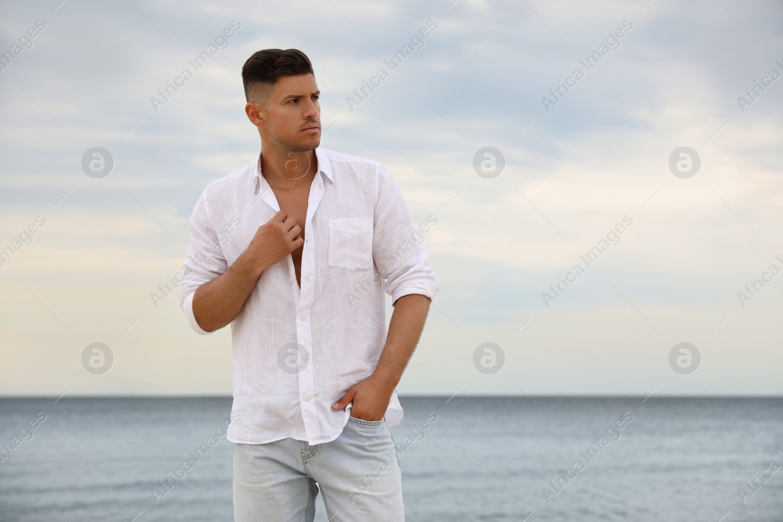Photo of Handsome man on beach near sea. Space for text
