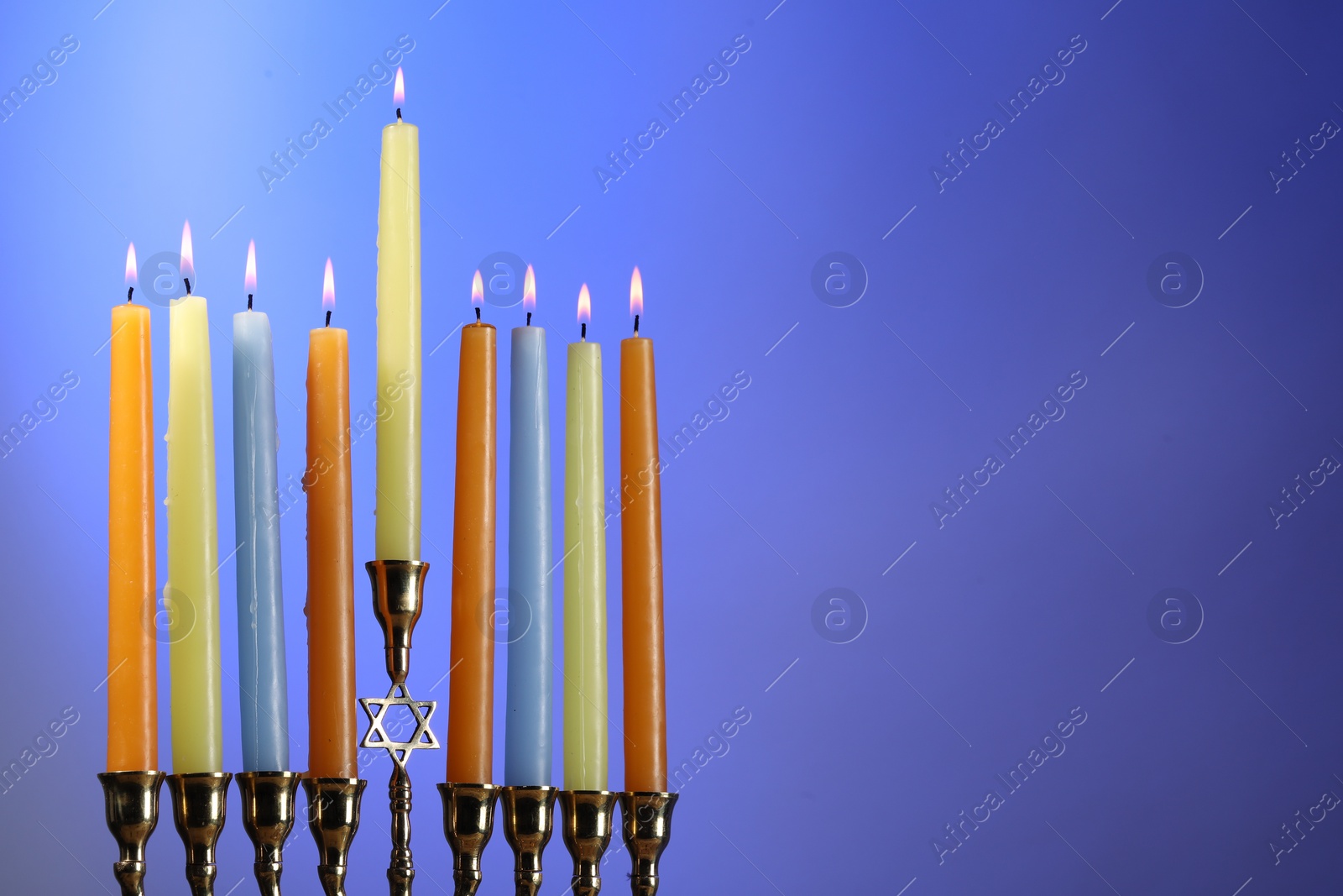 Photo of Hanukkah celebration. Menorah with burning candles on blue background, space for text