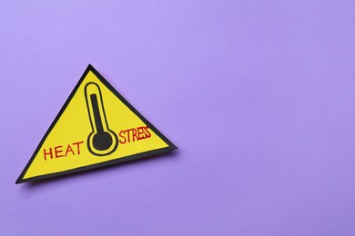 Photo of Yellow paper triangle with words Heat Stress and thermometer on violet background, top view. Space for text